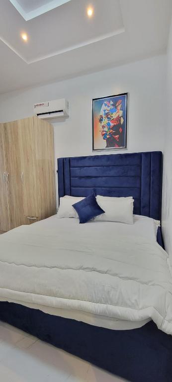 1 cama grande con cabecero azul en un dormitorio en Blue Luxury, en Awoyaya