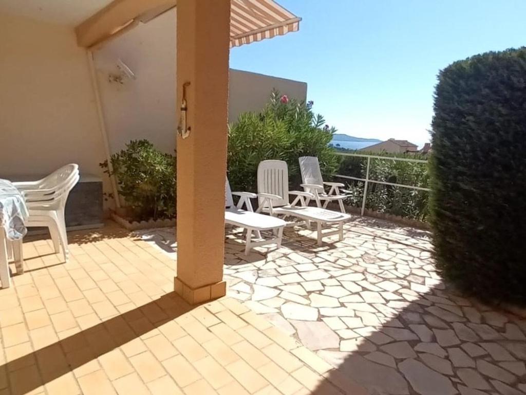 d'une terrasse avec des chaises blanches, une table et une clôture. dans l'établissement Charmant 2P avec jardin, piscine, parking et navettes gratuites - Cavalaire-sur-Mer - FR-1-226B-196, à Cavalaire-sur-Mer