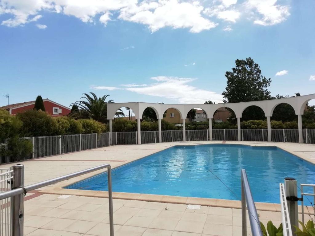 a swimming pool in a courtyard with a fence at Maison Vendres, 3 pièces, 4 personnes - FR-1-701-82 in Vendres