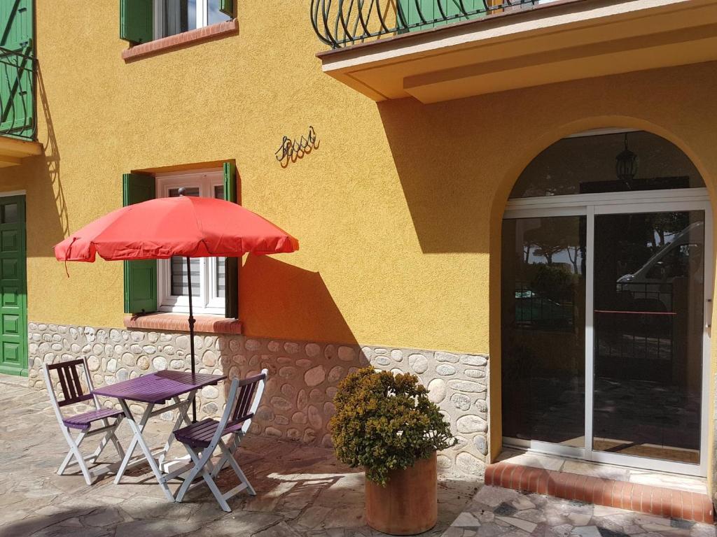 une table et des chaises sous un parasol à l'extérieur d'un bâtiment dans l'établissement Appartement rénové à 50m de la plage avec jardin et WIFI - FR-1-776-94, à Argelès-sur-Mer