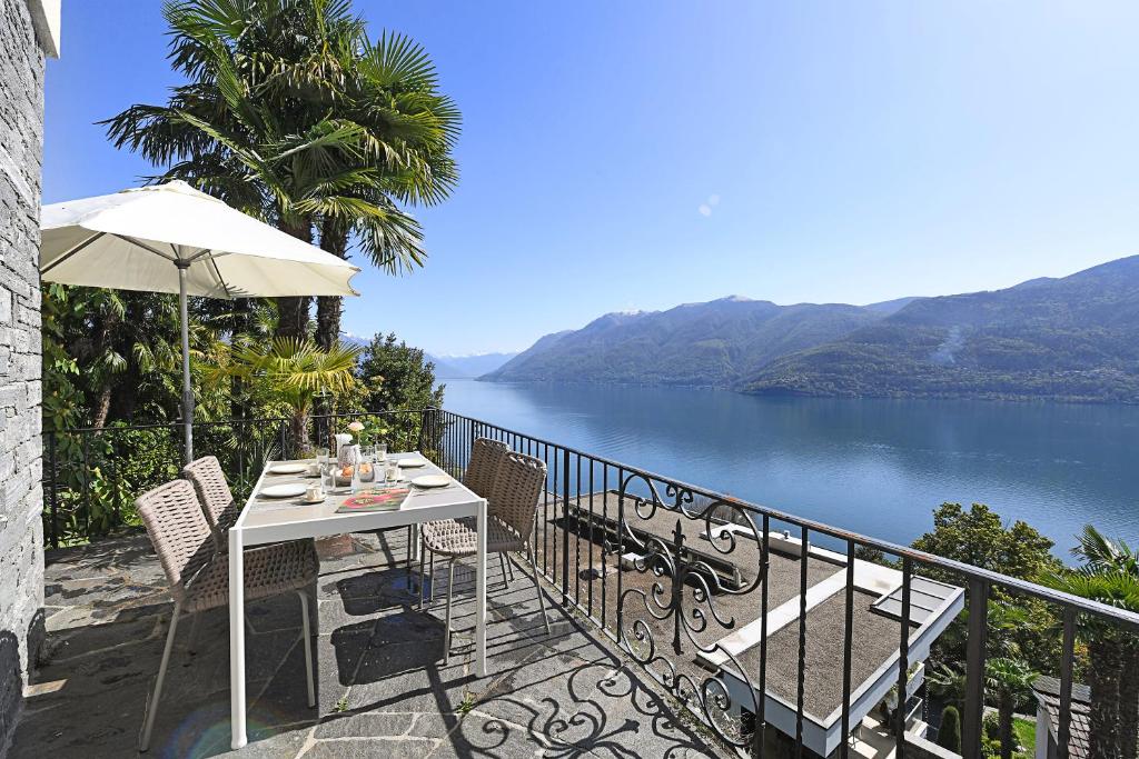 a table and chairs on a balcony with a view of a lake at Peace Over The Lake Rooms - Happy Rentals in Brissago