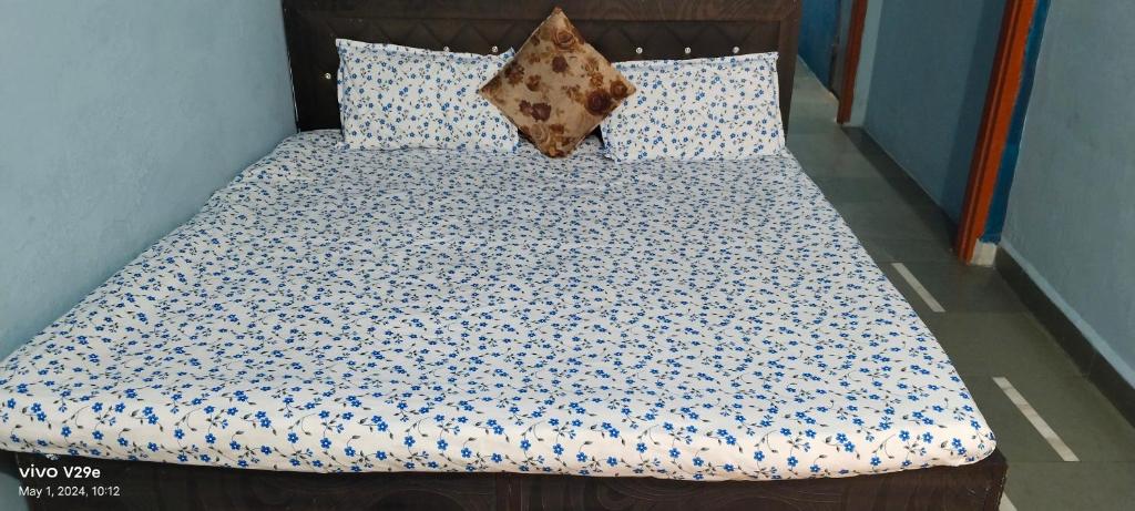 a bed with blue and white sheets and pillows at Shree Mangalnath Homestay in Ujjain