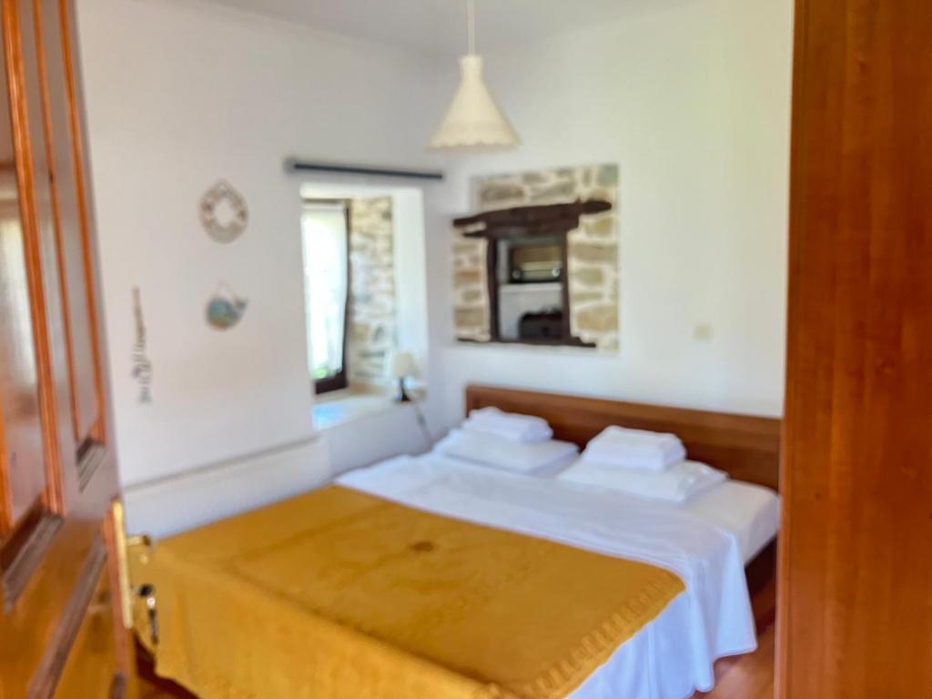 um quarto com uma cama com lençóis brancos e uma janela em Traditional house em Nikiti