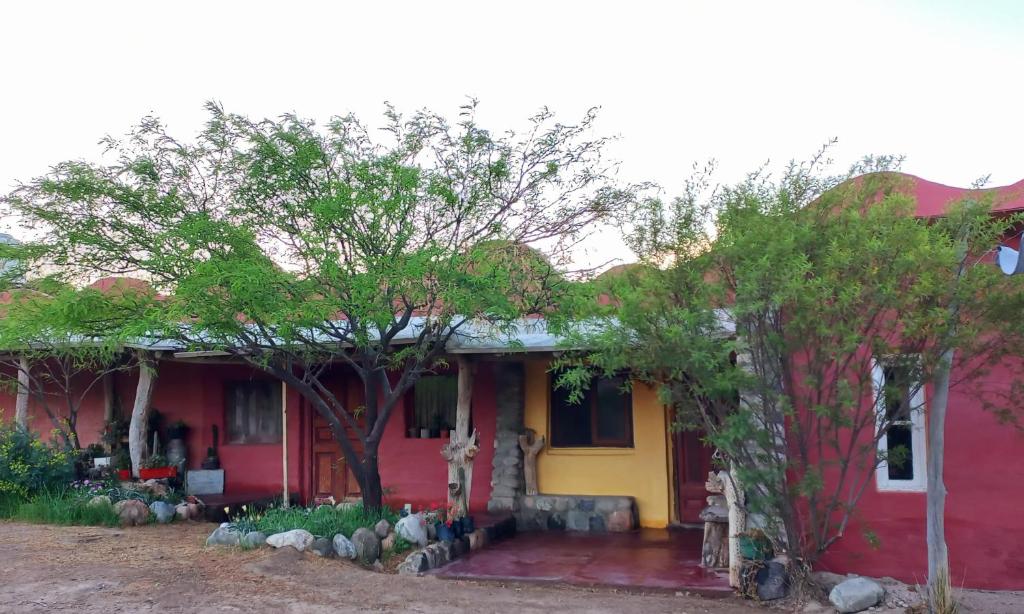una casa roja y amarilla con árboles delante en willkasunco Casa Hospedaje in 