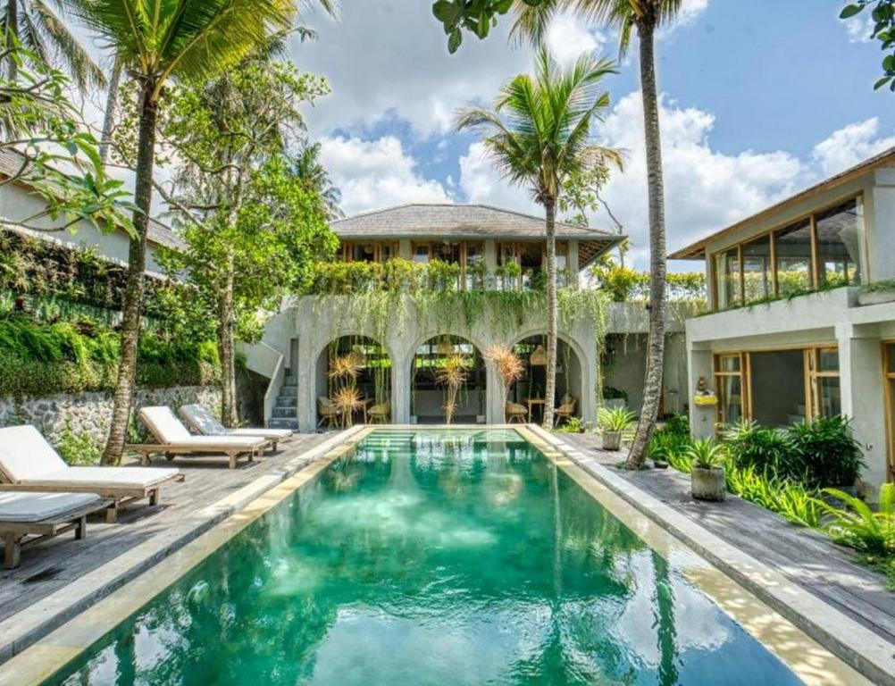 a swimming pool in front of a house with palm trees at Ubud Terrace by Betterplace in Ubud