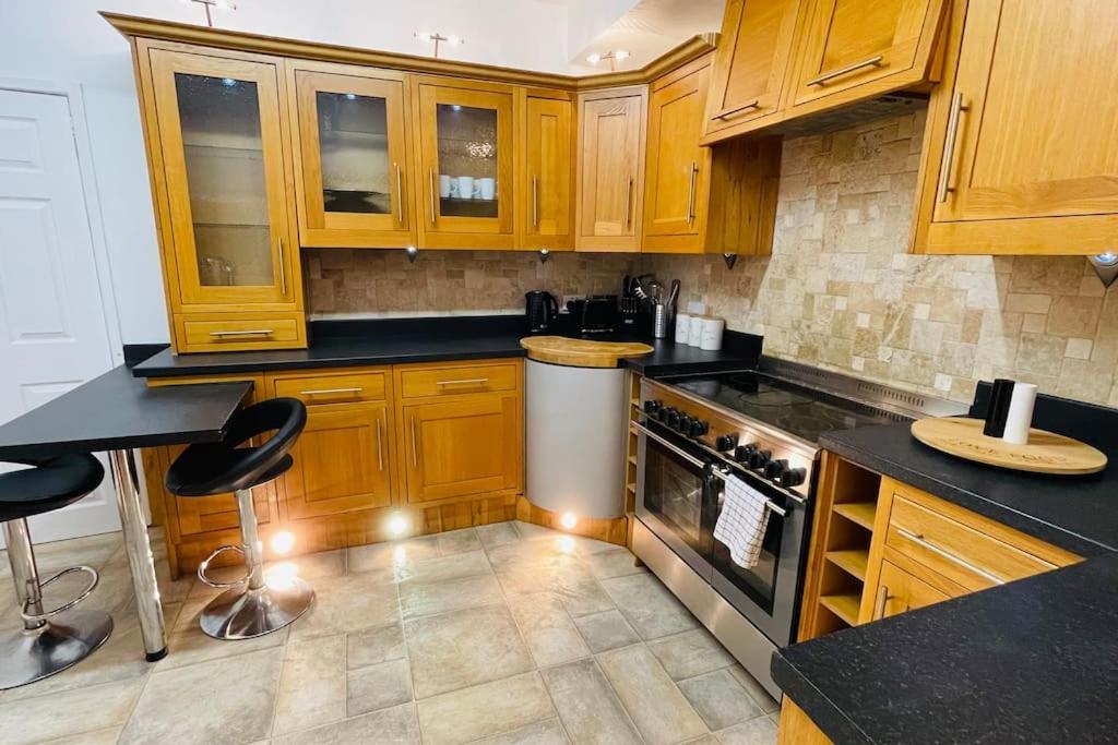 una cocina con armarios de madera y encimeras negras en King-size bed en- suit, Luxury refurbished home en Balderton