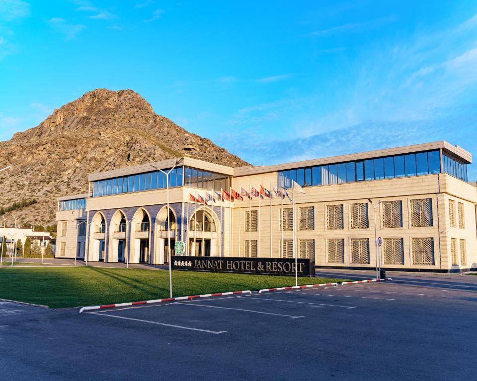 un gran edificio con una montaña en el fondo en Jannat Resort Osh en Osh