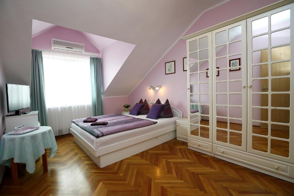 a bedroom with a bed with purple walls and wooden floors at Cecey Vendégház in Eger