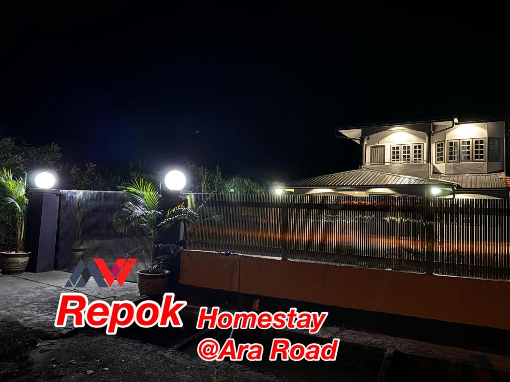 a house at night with lights on a fence at REPOK HOMESTAY in Sarikei