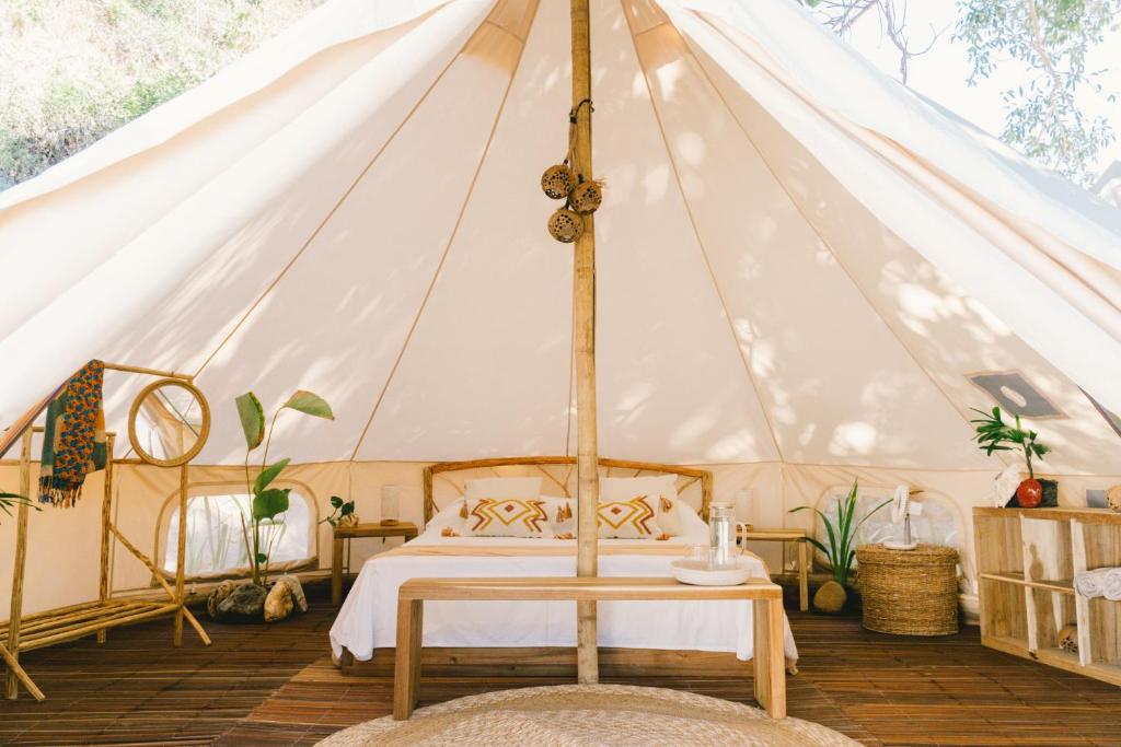 um quarto com uma tenda com uma cama e uma mesa em Parada Beach Camp em El Nido