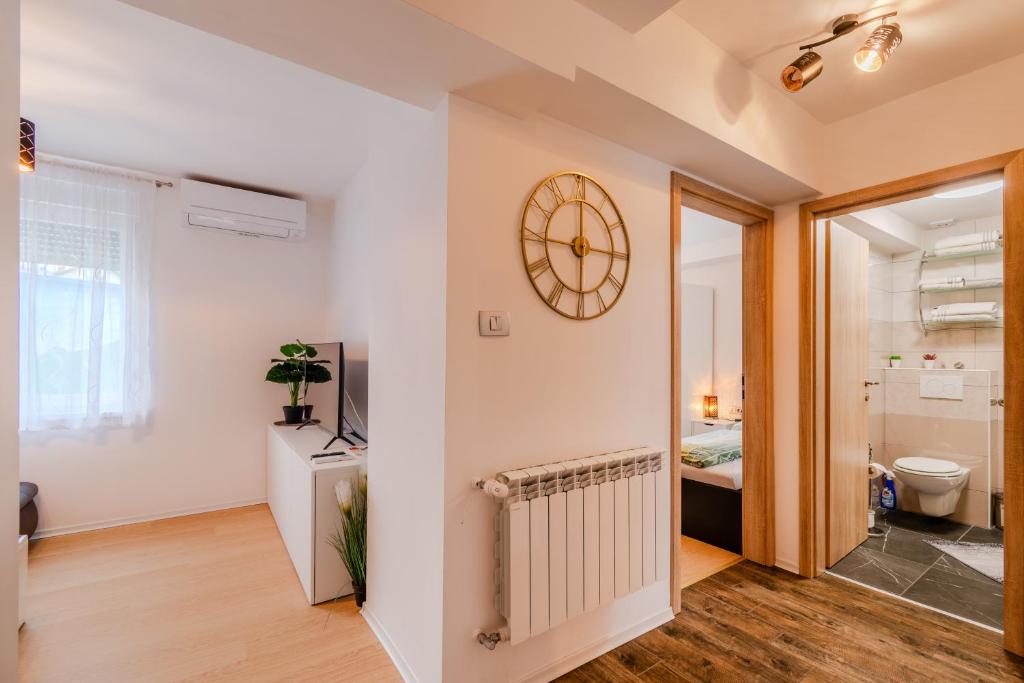 a room with a clock on the wall and a bathroom at Apartmaji Hosnar, apartma Lev in Bovec