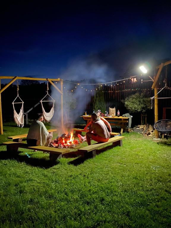 a group of people sitting around a fire at night at Bieszczadzkie BOHO stodoły z jacuzzi i sauna na wyłączność in Myczkowce