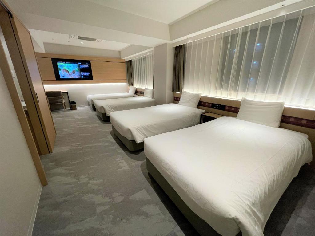 a hotel room with three beds and a flat screen tv at Henn na Hotel Premier Nara in Nara