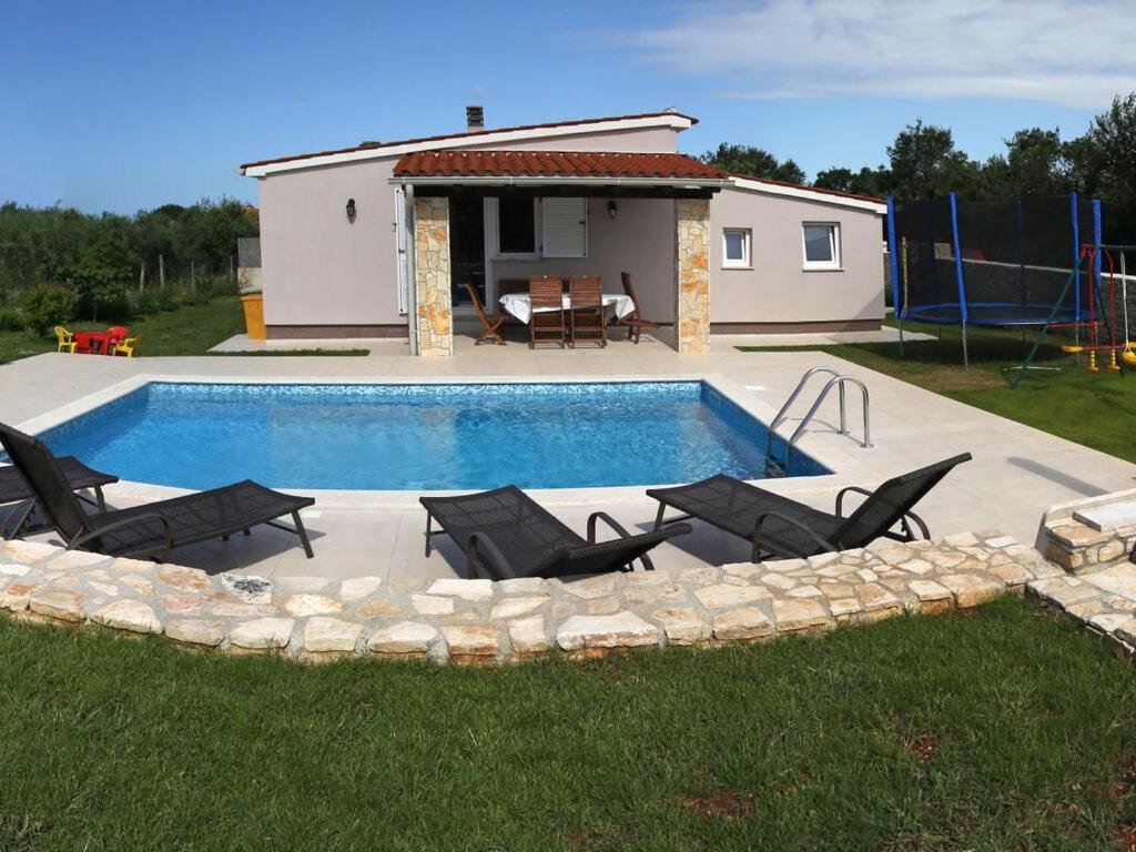 uma piscina com um grupo de cadeiras e uma casa em Harriet Comfortable holiday residence em Loborika