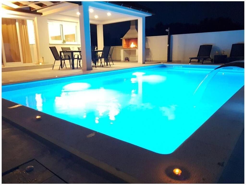 a swimming pool lit up at night at Villa Sabun Luxury Villa with Poo, Jacuzzi in Privlaka