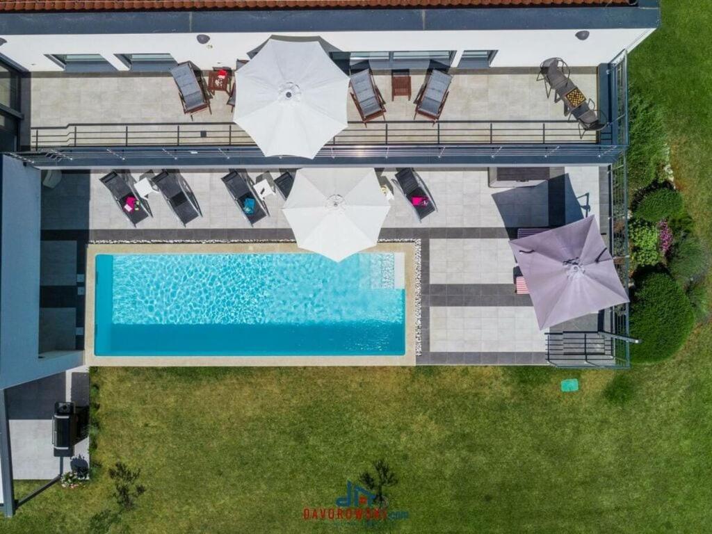 een uitzicht over een zwembad met tafels en parasols bij Elsa Comfortable holiday residence in Krnica