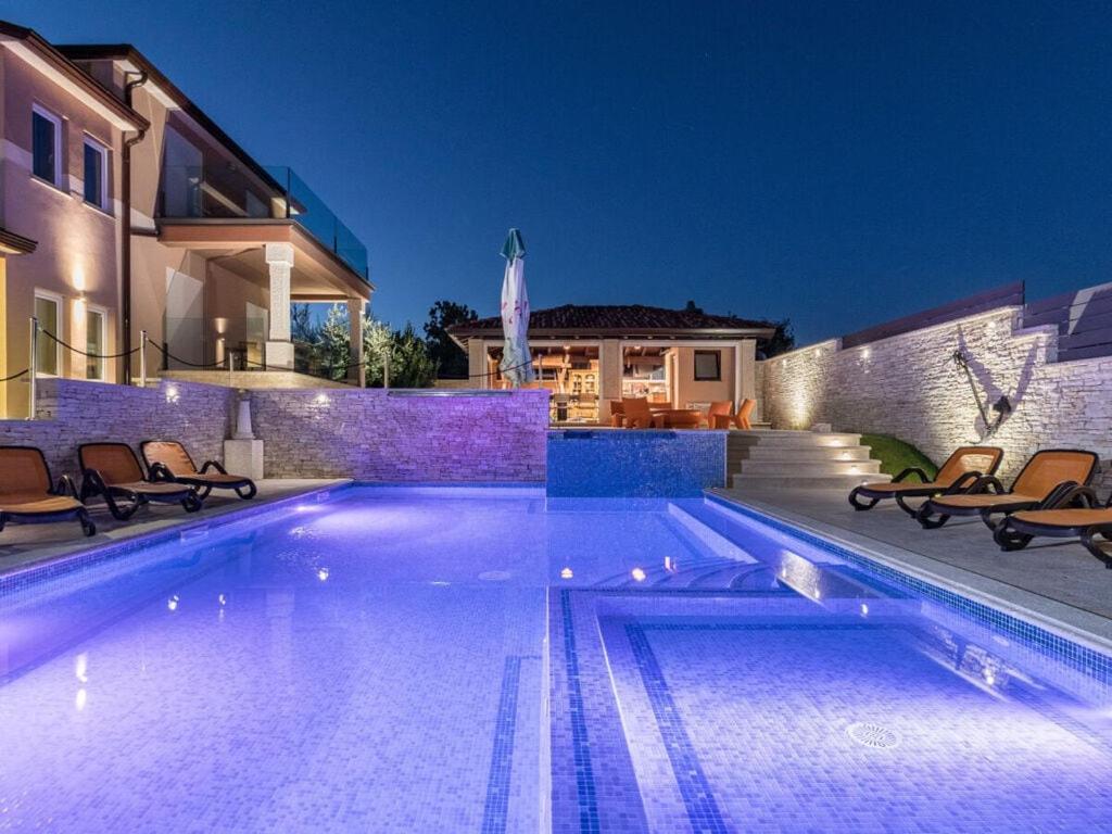 a swimming pool in front of a house at Istra Kamen Comfortable holiday residence in Valtura