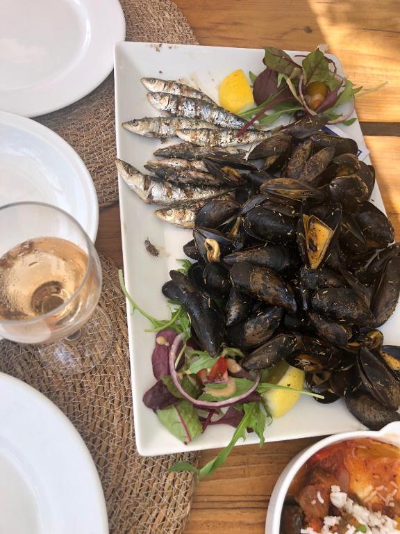 a plate of mussels and a salad with a glass of wine at Chez Skadi amazing sea view in Roquebrune-sur-Argens
