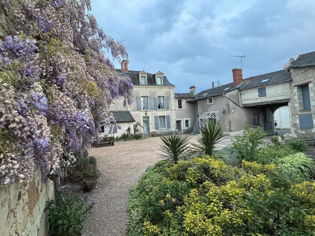 Una casa con flores púrpuras a un lado. en The Old Winery, Loire, en Le Puy-Notre-Dame