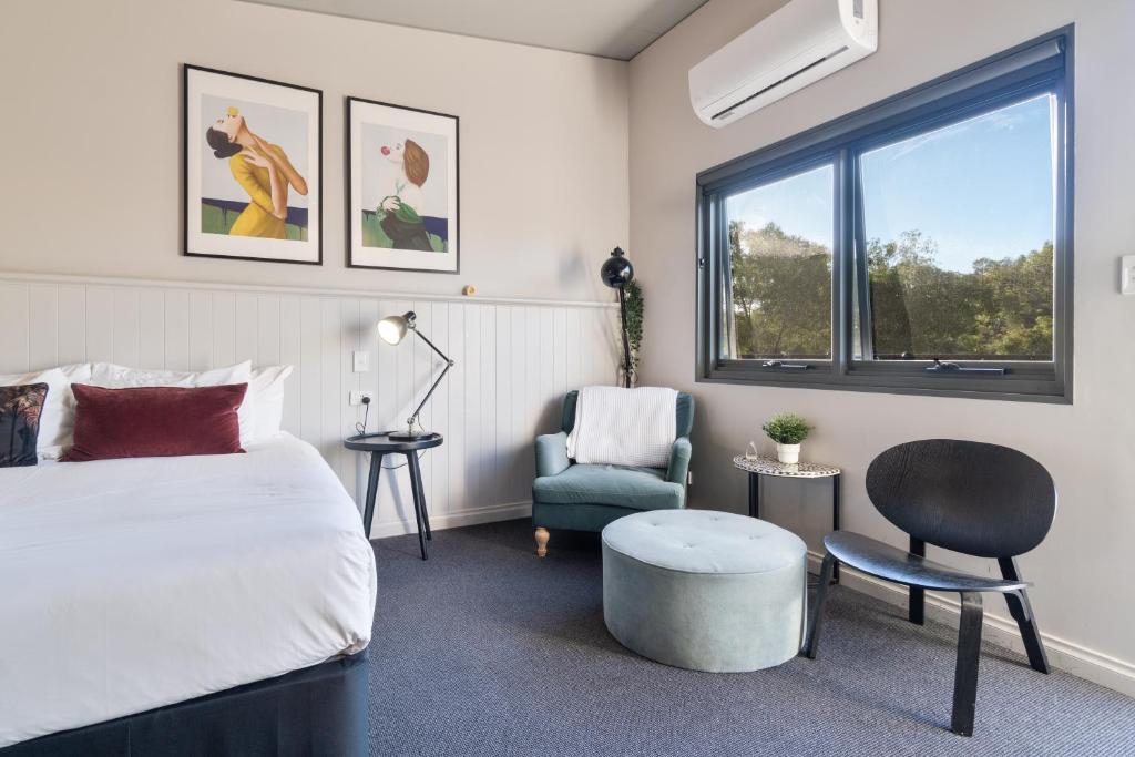 a bedroom with a bed and a chair and a window at Victoria Hotel Toodyay in Toodyay