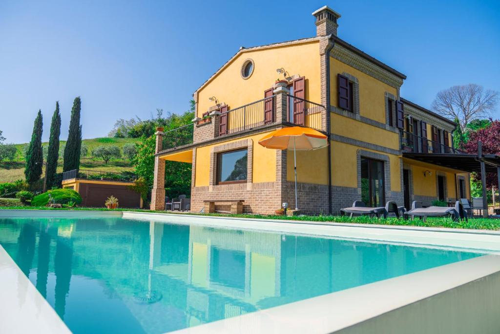 ein Haus mit einem Pool vor einem Gebäude in der Unterkunft Villa Fortuna Belvedere in Montegranaro