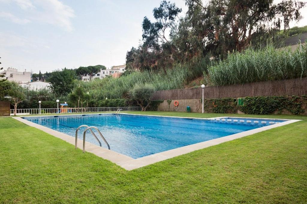 una piscina en un patio con césped en LUDERNA - Apartamento Dels tres micos del maresme, en Caldes d'Estrac