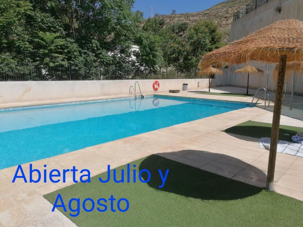 uma piscina com um guarda-sol e um resort em Casa de la Aldea 