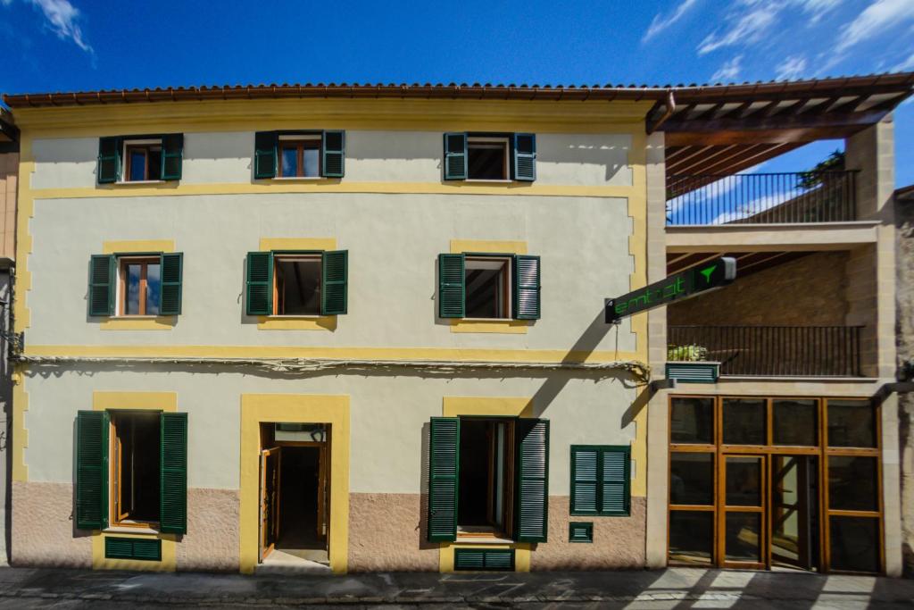 a building with green shuttered windows and a street sign at Embat - alberg juvenil in Montuiri