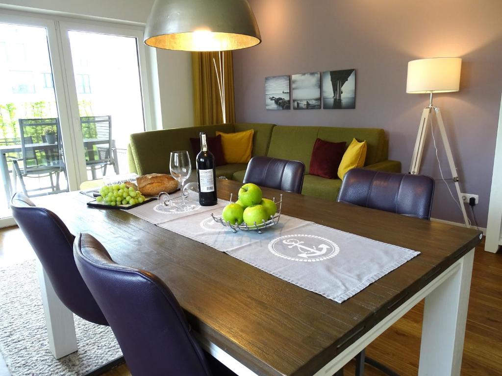 a dining room table with a bottle of wine and fruit on it at Gode Wind Quartiere 1 in Dahme