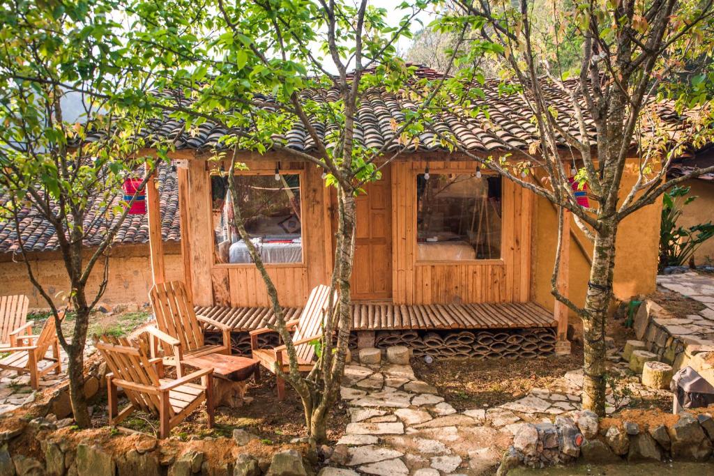 eine Hütte mit Stühlen und eine Veranda mit Bäumen in der Unterkunft Then Pa village in Loung Co