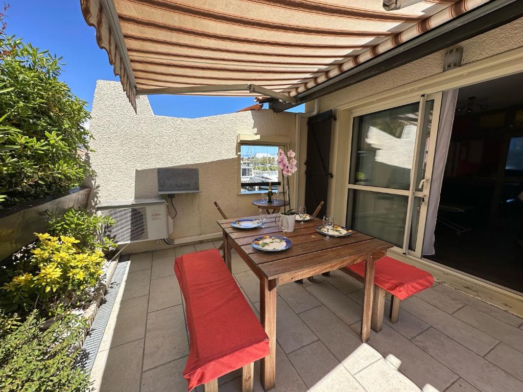 une table et des chaises en bois sur une terrasse dans l'établissement Village naturiste - Port-Vénus - Villa Betty Boop, au Cap d'Agde