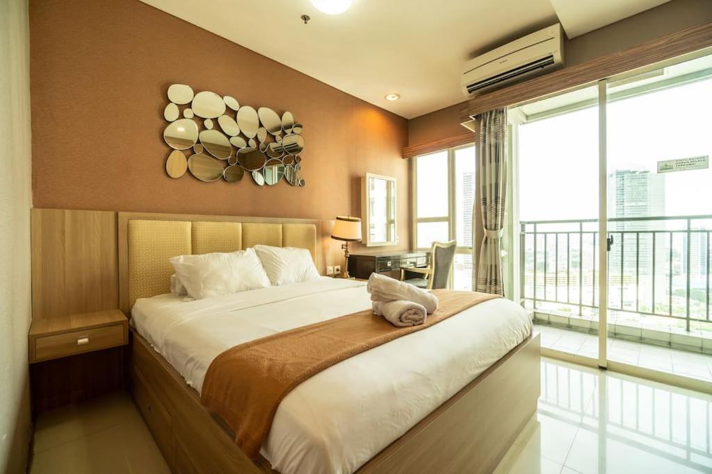 una camera da letto con un letto grande e una grande finestra di 1BR Near GI Mall Thamrin, SCBD a Giacarta