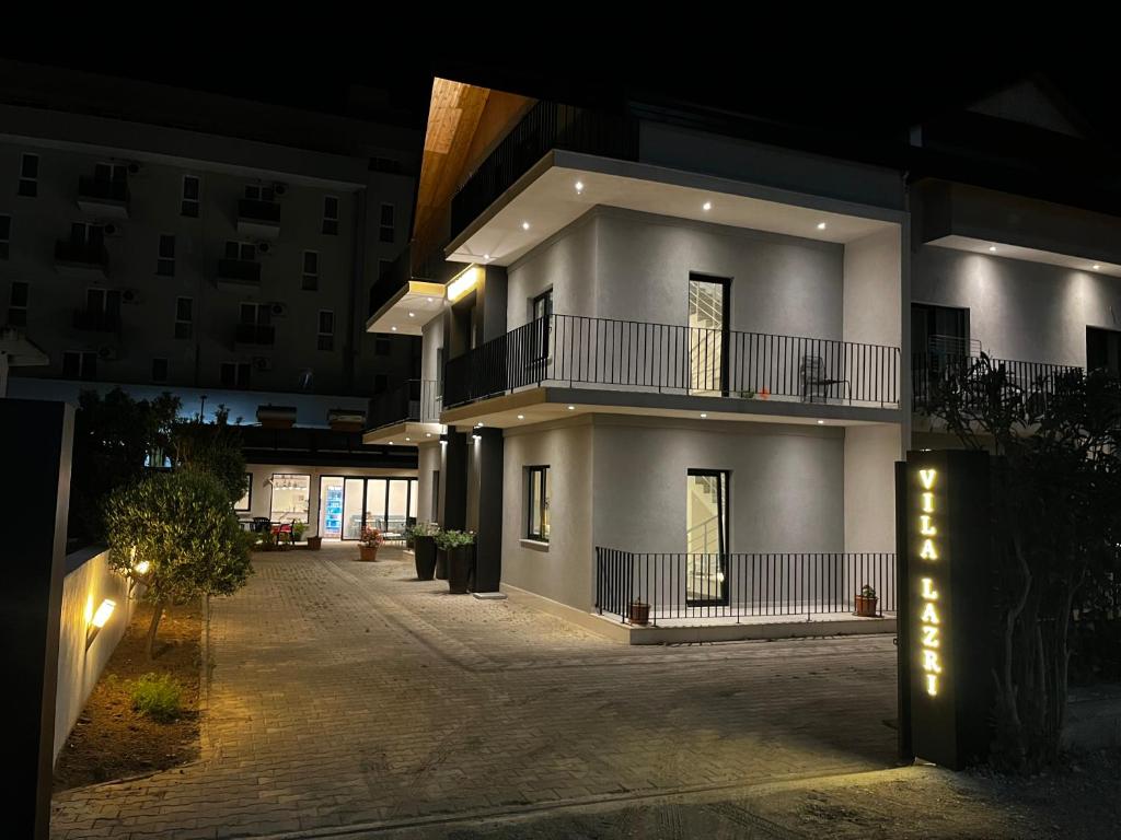 un gran edificio blanco con balcón por la noche en Vila Lazri, en Skataj