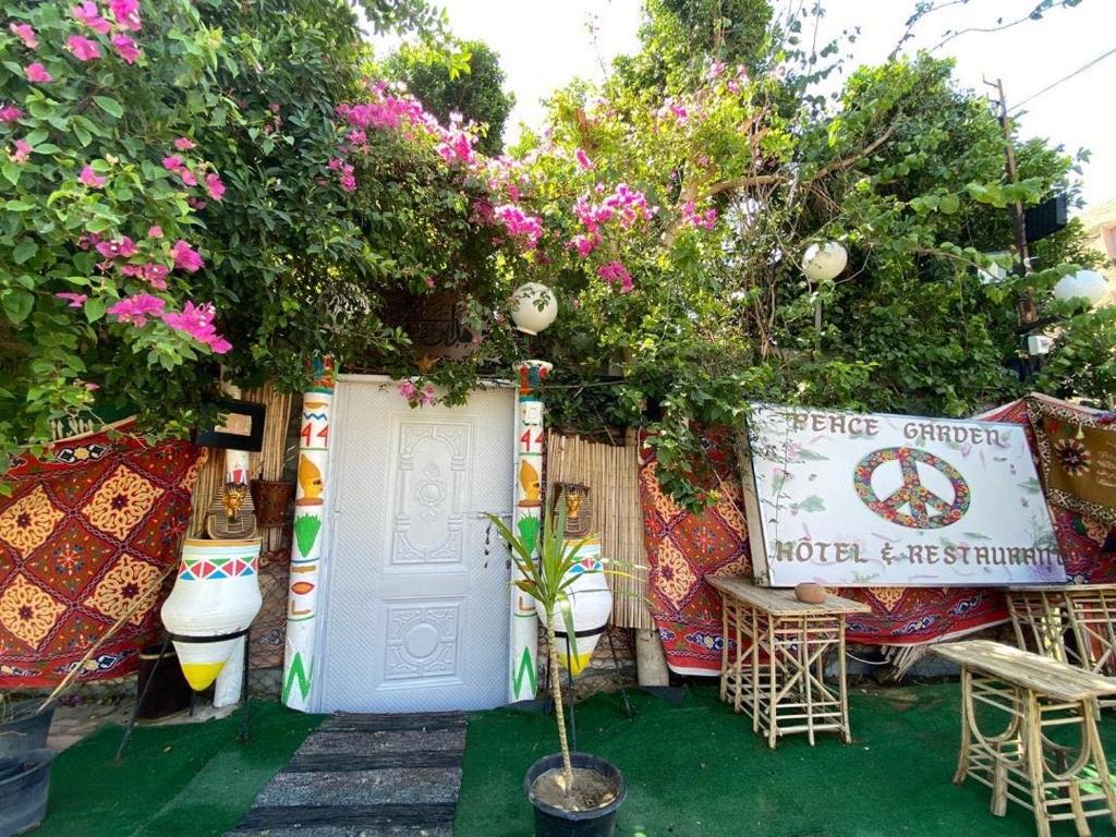 a garden with a white door and some pink flowers at peace garden hostel & camp in Luxor