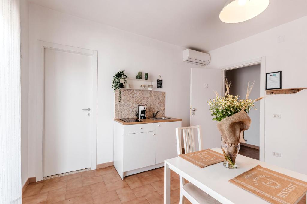 a kitchen with white cabinets and a table with a vase of flowers at Acquaterra in Polignano a Mare