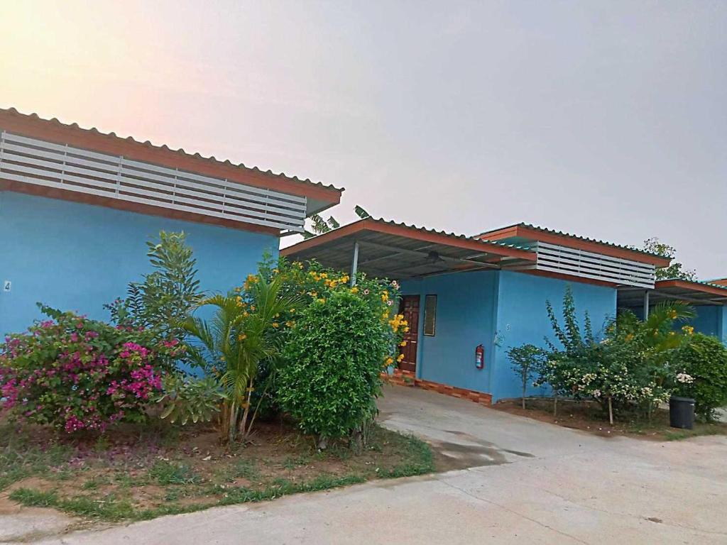 una casa azul con flores y plantas delante de ella en OYO 75488 Leelawadee View Resort (Amnatcharoen) en Amnat Charoen