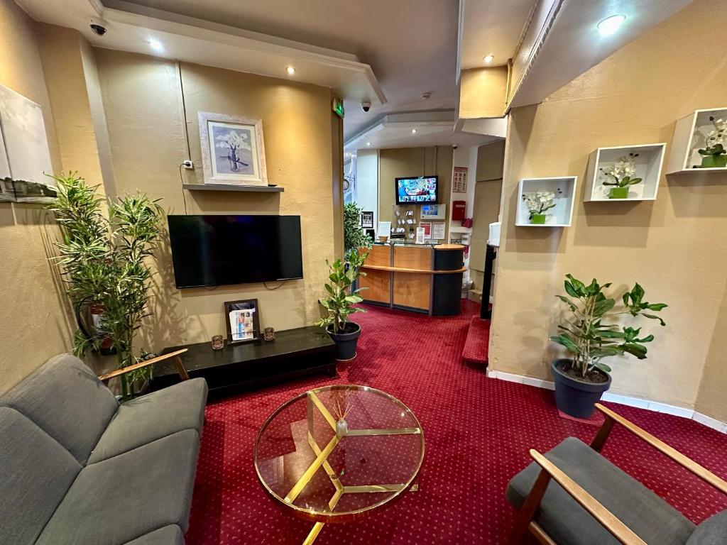 a lobby with a waiting room with plants and a tv at Hotel Victor Hugo in Clamart