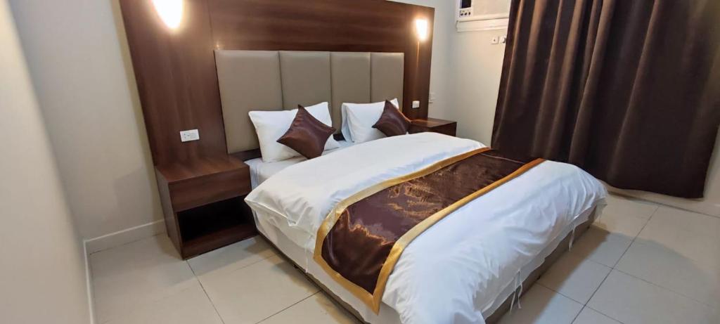 um quarto com uma cama grande e uma cabeceira em madeira em شقق العييري المخدومة الباحة 02 em Al Baha