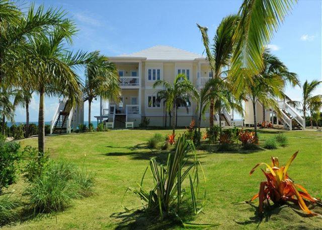 una casa grande con palmeras delante en Coastal Haven: Charming Beachfront Cottage with Pool, en James Cistern