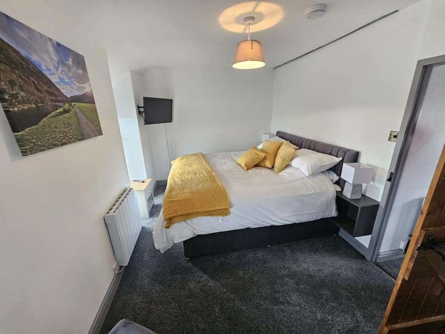 Un dormitorio con una cama con almohadas amarillas. en cosy cottage in snowdonia en Brynkir