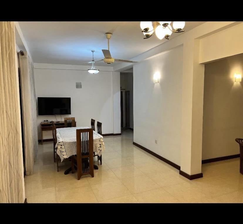 una sala da pranzo con tavolo, sedie e TV di Araliya Uyana Apartments - Two Bed Room House a Ratmalana