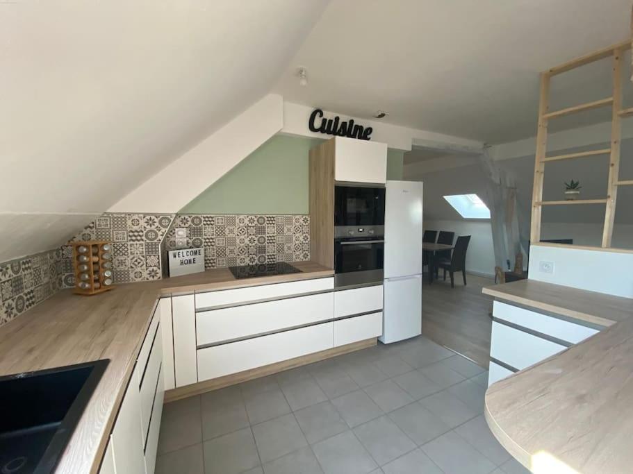 une grande cuisine avec des armoires et des appareils blancs dans l'établissement Chez Salomé & Théo !, à Saint-Jean-dʼArvey