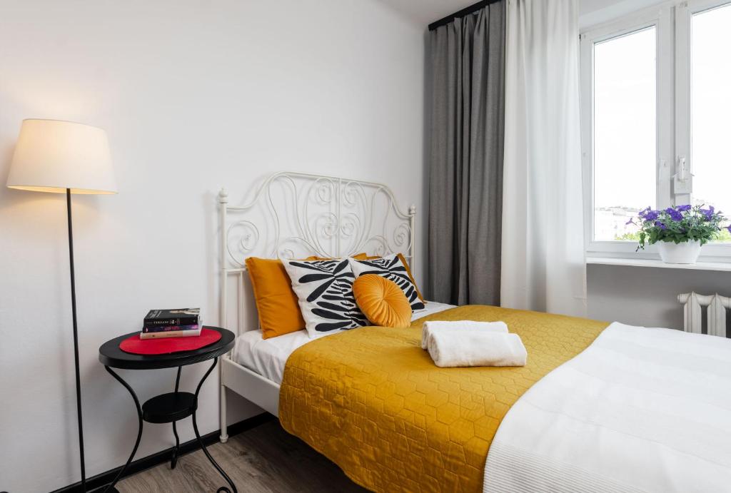 a bedroom with a bed with a yellow blanket and a table at Rose Corner Rozana Mokotow in Warsaw