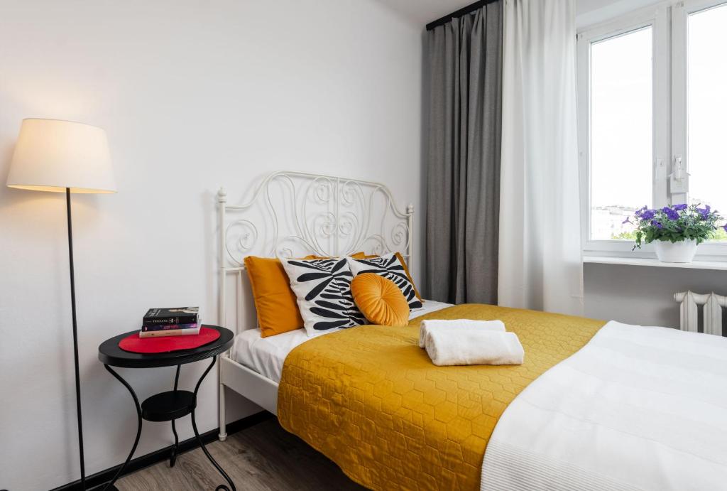 ワルシャワにあるRose Corner Rozana Mokotowのベッドルーム1室(黄色い毛布とテーブル付きのベッド1台付)
