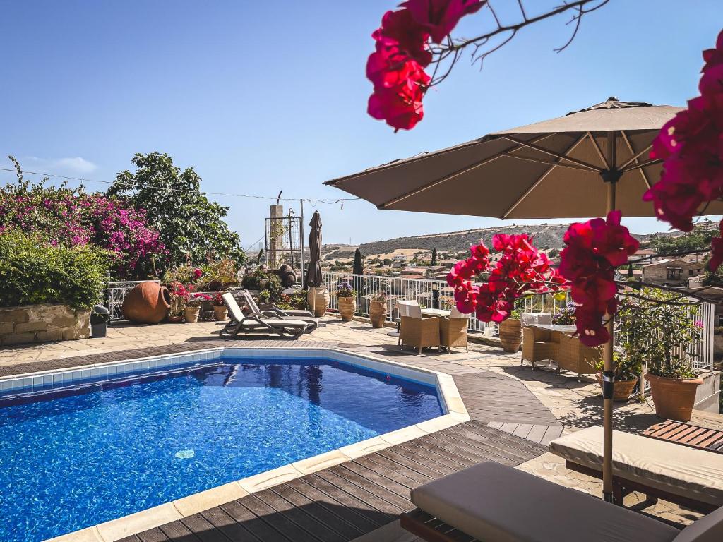 a swimming pool with an umbrella and chairs at Cyprus Villages Hotel & Restaurant - Central Location - Bed & Breakfast - With Access To Pool And Stunning Views in Tochni