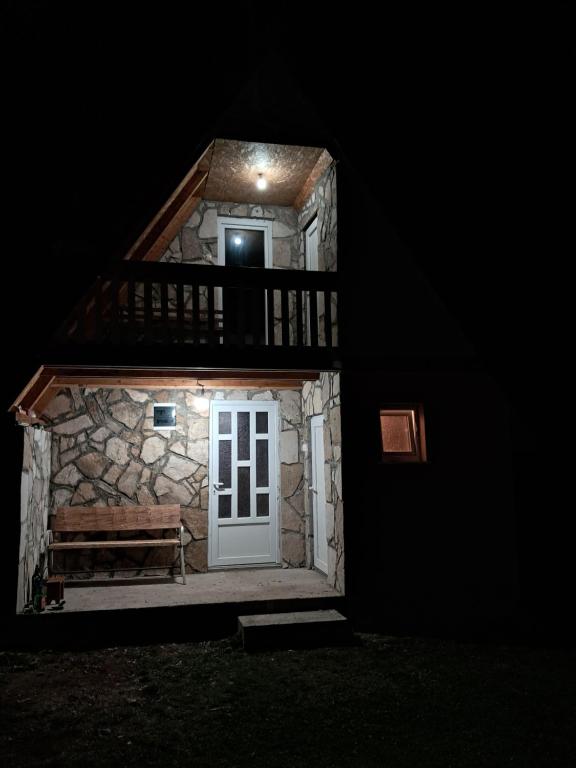 a building with a door and a bench in the dark at Village House Djurovic in Pošćenje