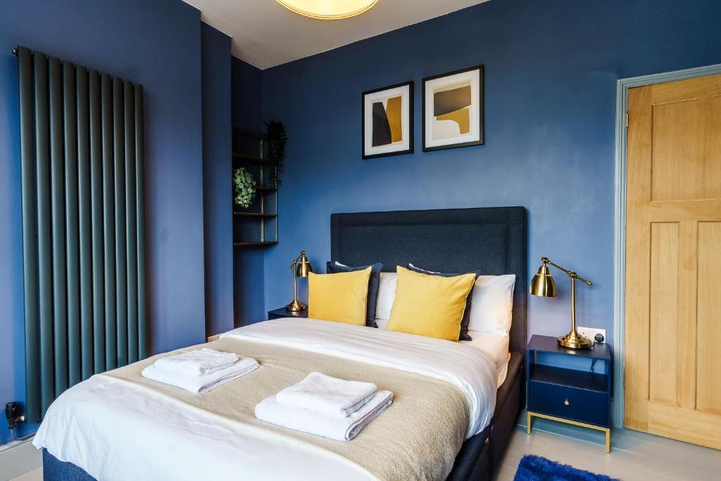 sypialnia z niebieskimi ścianami i łóżkiem z żółtymi poduszkami w obiekcie Family House Garden Netflix Games FreeParking w Cardiff