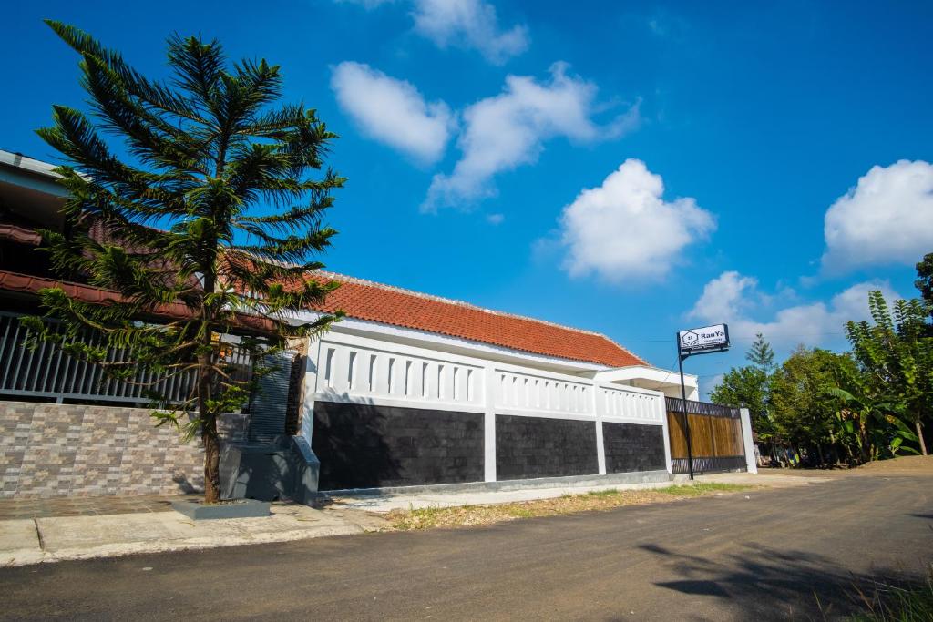 a building with a palm tree next to a street at Ranya Homestay in Purwokerto