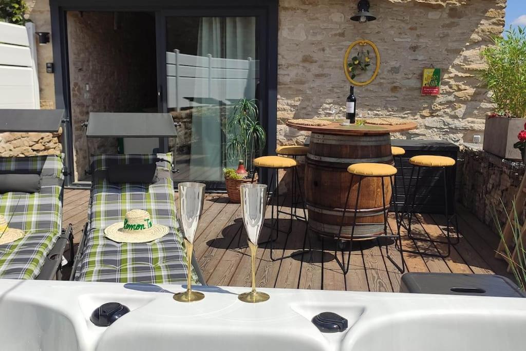 a table with two wine glasses on a wooden deck at Jacuzzi au Lemon Tree et charme des pierres dorées in Panossas