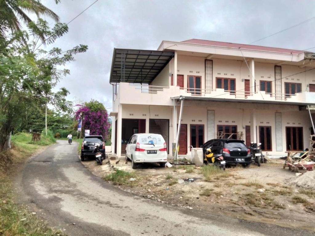 a house with cars parked on the side of a road at NADELS HOMESTAY SYARIAH in Gadut